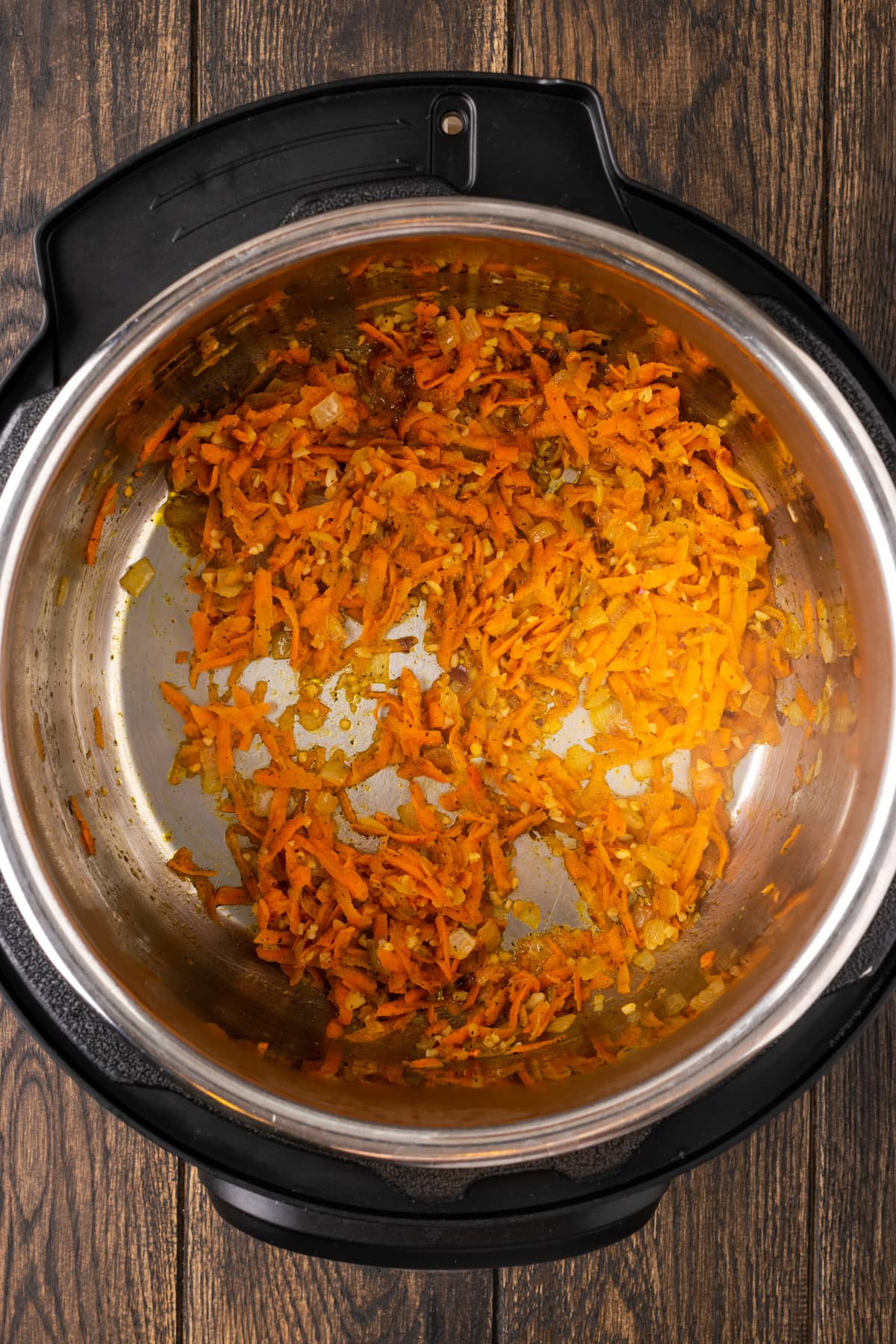 Zanahorias y cebollas salteadas en el fondo de una olla instantánea.