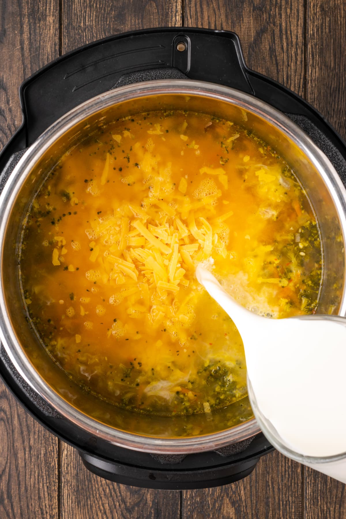 La mitad y la mitad se vierte en la olla instantánea con los otros ingredientes para la sopa de brócoli y queso cheddar.