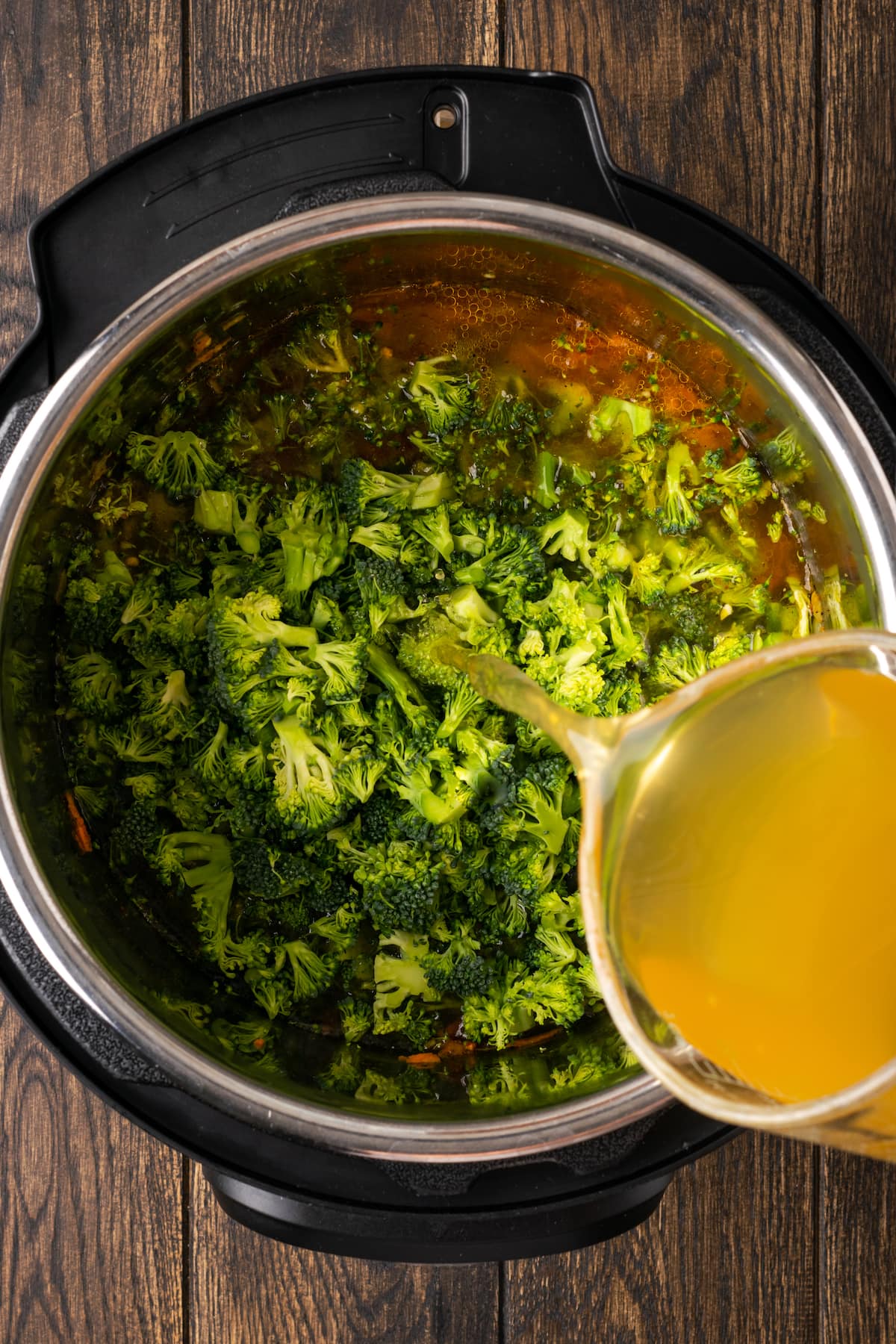 El caldo se vierte sobre el brócoli cortado en cubitos y las verduras en la olla instantánea.