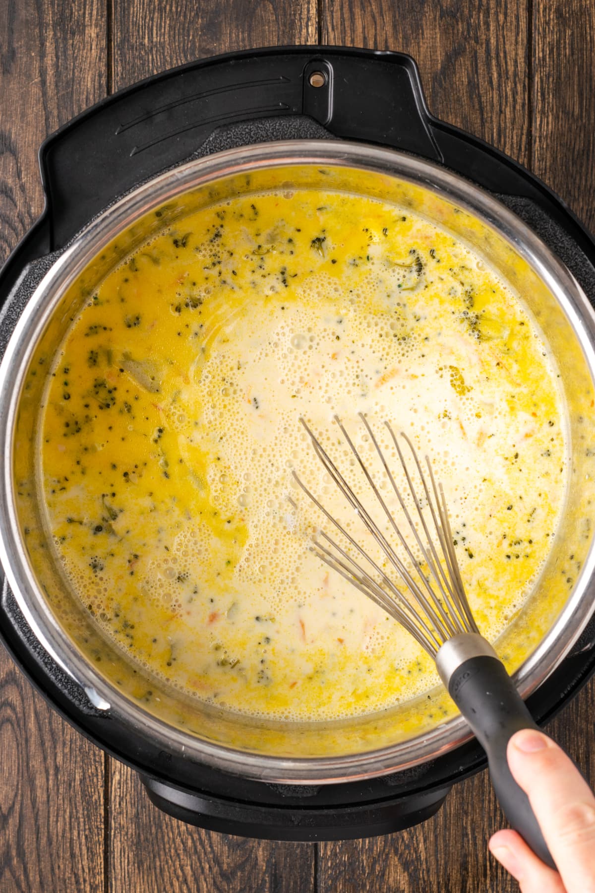 Se usa un batidor para revolver la sopa de brócoli y queso cheddar dentro de la olla instantánea.
