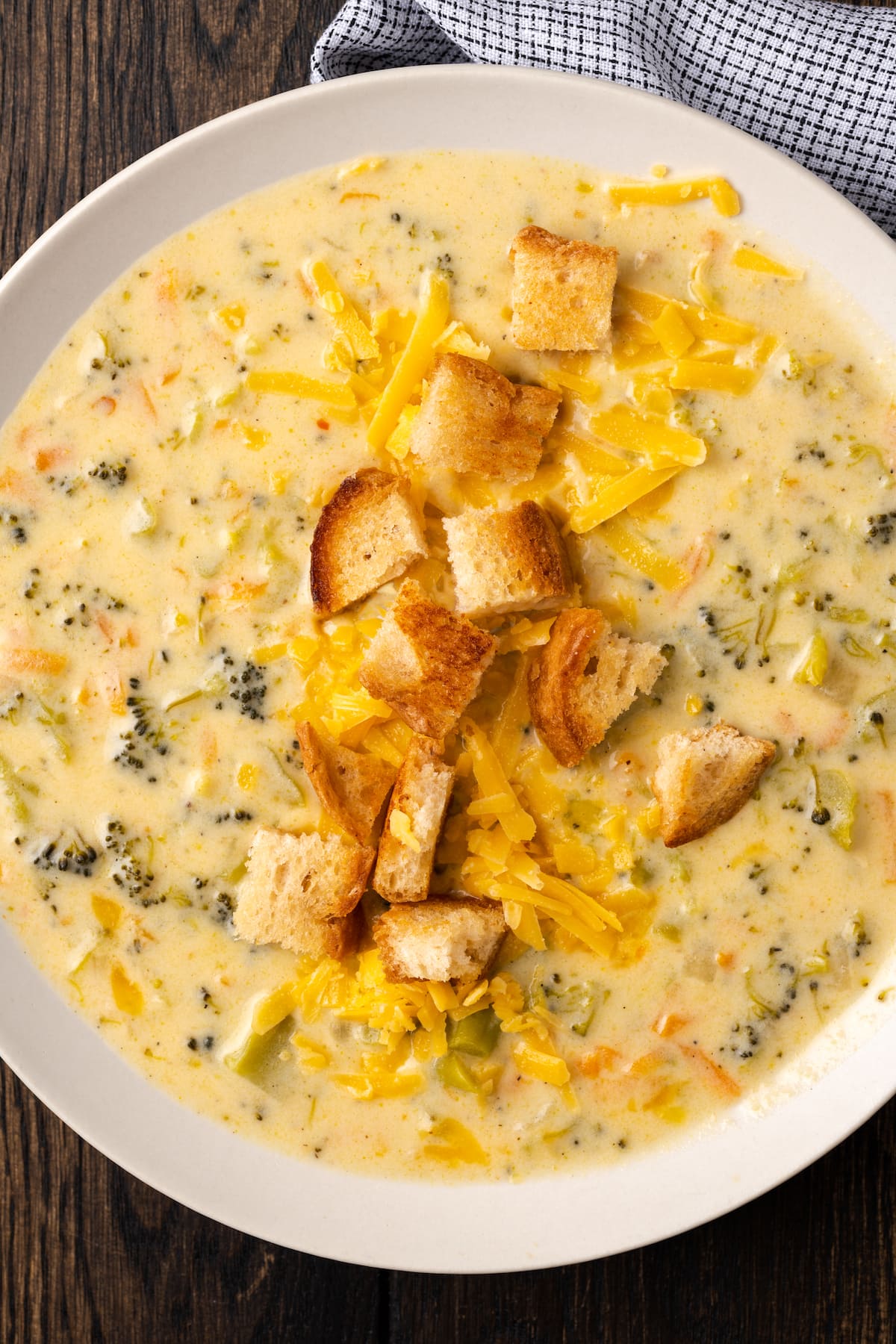 Vista aérea de un tazón de sopa instantánea de brócoli y queso cheddar cubierta con picatostes.
