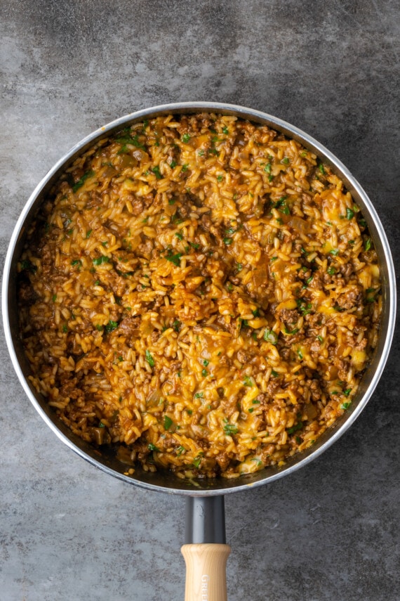 Arroz de taco terminado cubierto con queso derretido en una sartén.