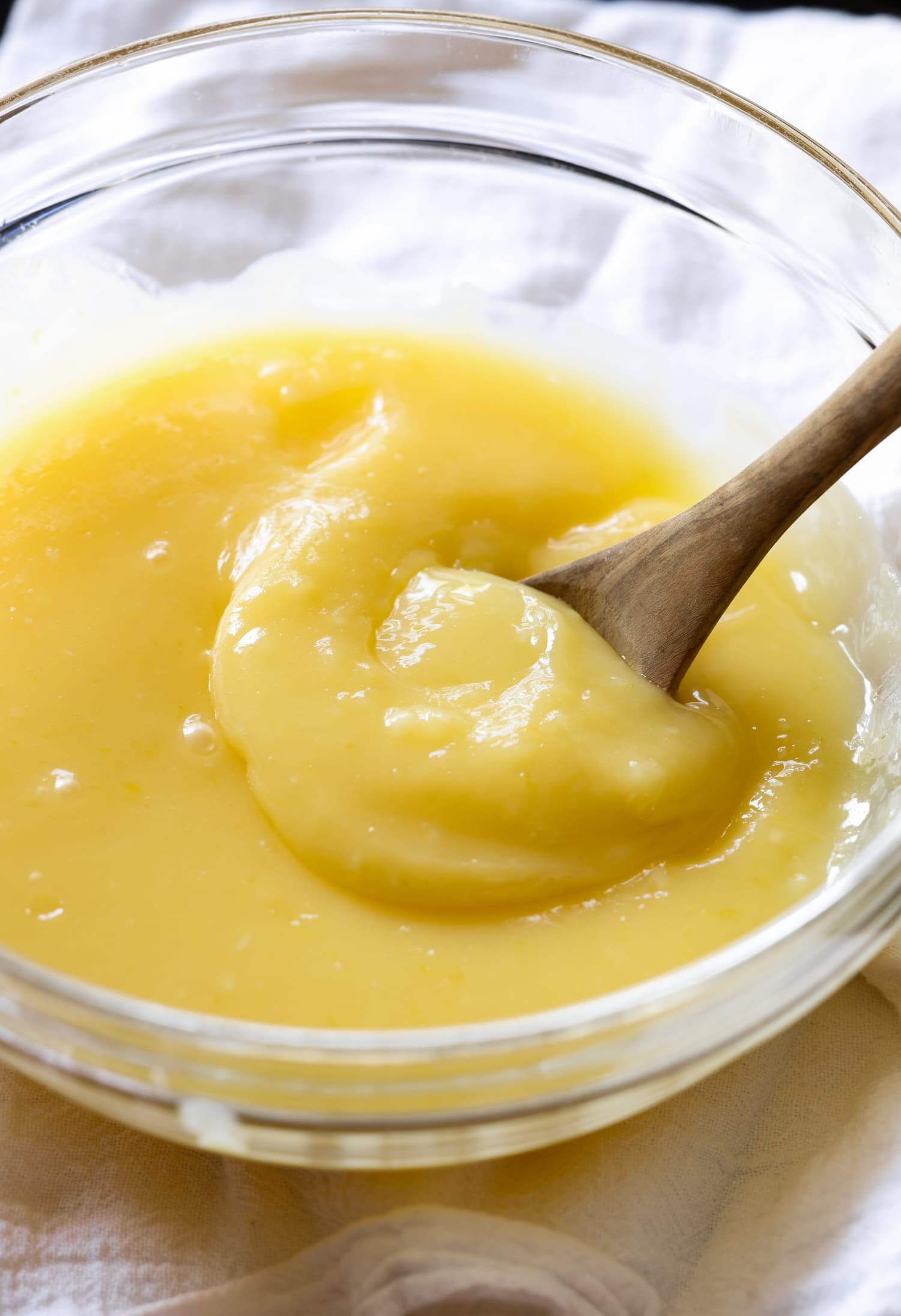 Mi receta casera de Lemon Curd es una crema de limón dulce perfecta para hornear, rellenar pasteles o tartas o como complemento para la crema del desayuno. Cuajada de limón casera caliente en un bol con una cuchara