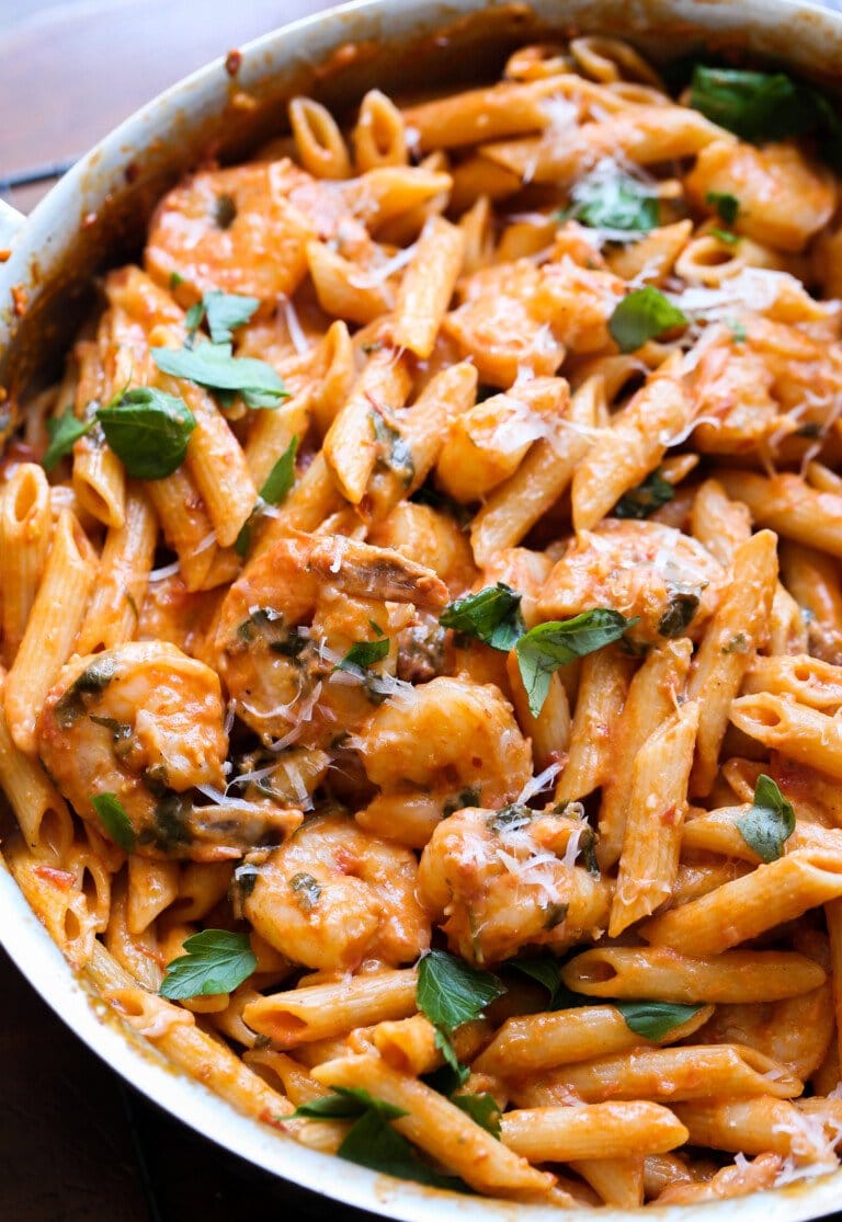 Pasta cremosa de camarones en una sartén grande con guarnición de albahaca fresca