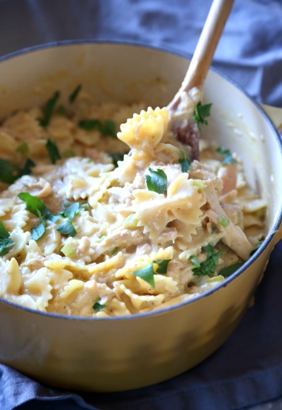 Pollo con queso y pasta de pajarita en una olla grande con una cuchara para servir.