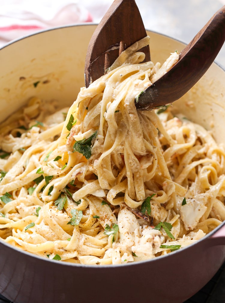 Las pinzas se usan para levantar la pasta alfredo de cangrejo de una olla grande.