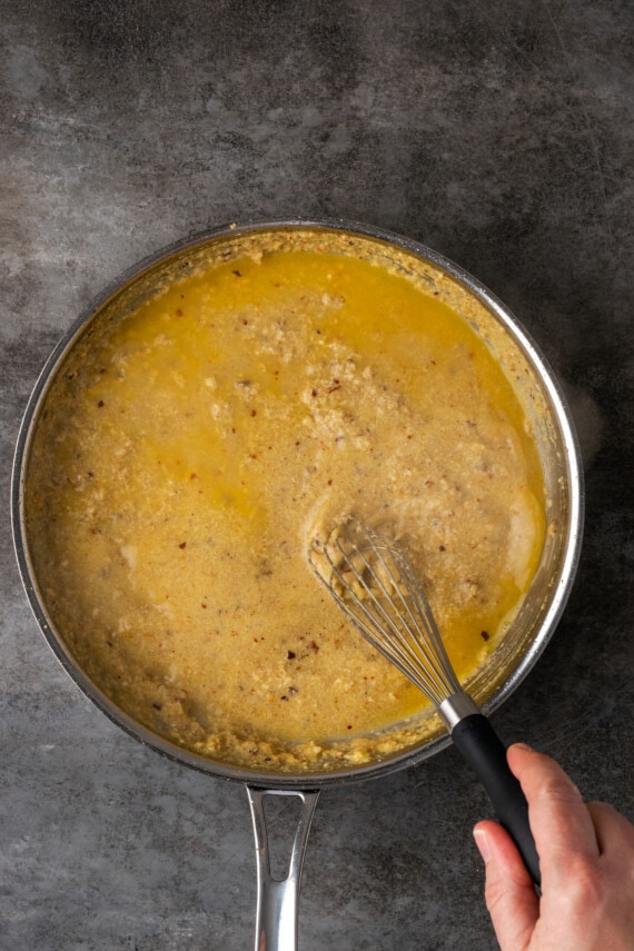 Ingredientes de la salsa César para pasta batidos en una sartén.