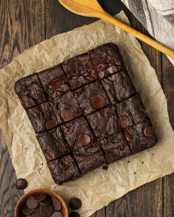 Vista aérea de brownies de mezcla para pastel cortados en cuadrados en una hoja de papel pergamino.
