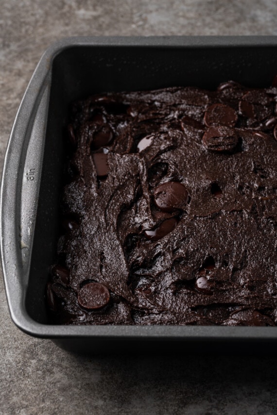 Mezcla para pastel La masa de brownie se esparce en un molde para hornear de metal cuadrado.