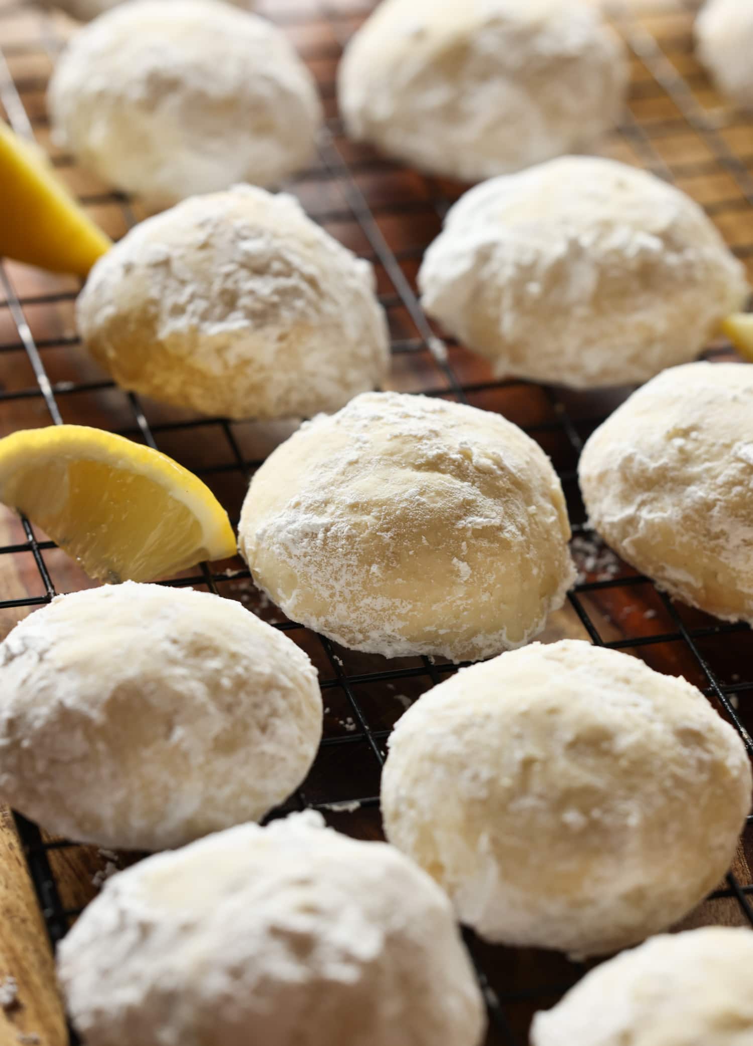 Mis galletas fáciles de enfriar con limón son galletas suaves, agrias y cítricas cubiertas con azúcar en polvo derretida. ¡La receta perfecta de galletas de limón! Lemon Cooler Cookies en una rejilla de cocción recubierta de azúcar en polvo