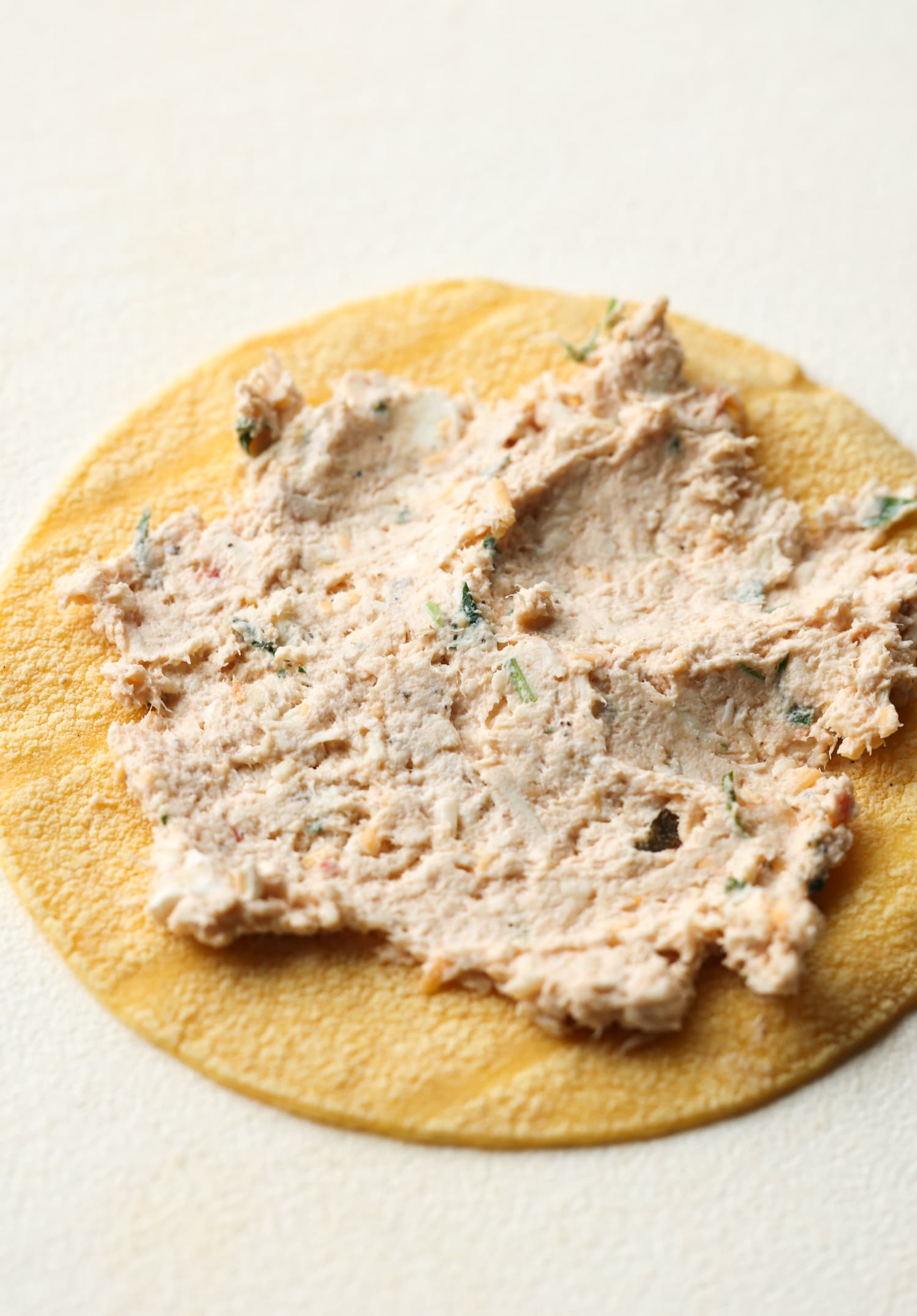 La receta de taquitos de pollo con queso son tortillas crujientes rellenas de pollo, quesos y condimentos, ¡una idea súper fácil para cenar en el área de los taquitos! extendiendo la mezcla de pollo sobre una tortilla de maíz