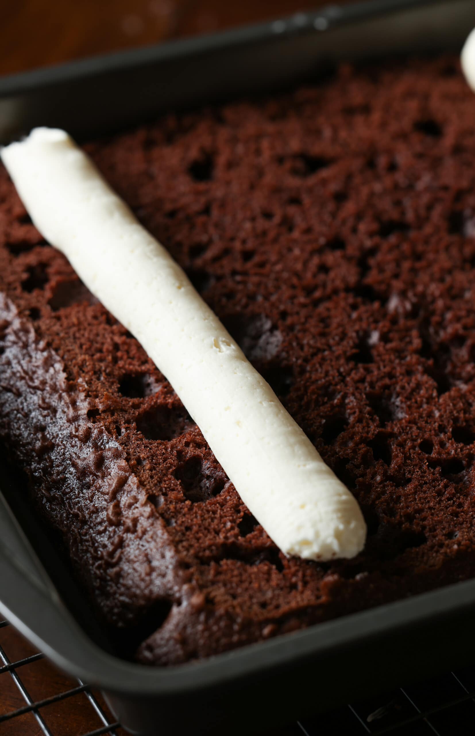 Un tubo entubado de glaseado de vainilla encima de un pastel de chocolate