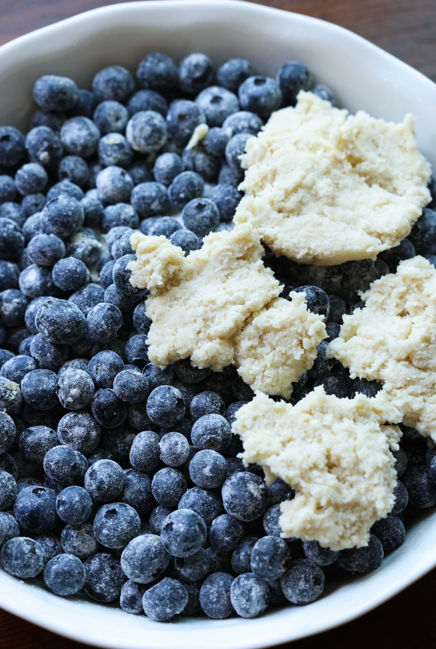 ¡Esta receta fácil de zapatero de arándanos es un postre clásico de verano que debes probar! Los arándanos dulces combinados con una cubierta de galleta mantecosa se hornean hasta que estén burbujeantes y dorados. arándanos en un plato de pastel con trozos de masa encima