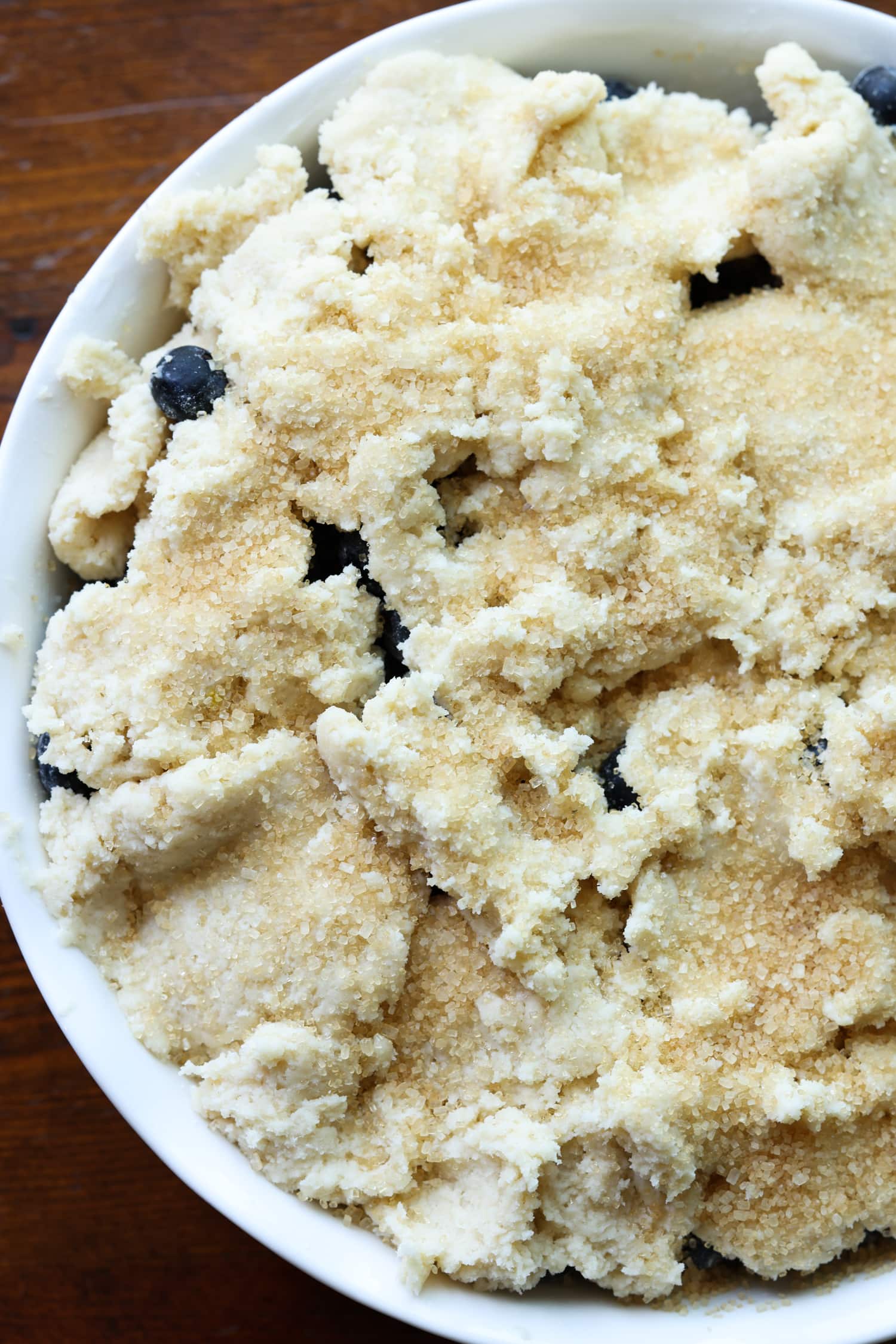 ¡Esta receta fácil de zapatero de arándanos es un postre clásico de verano que debes probar! Los arándanos dulces combinados con una cubierta de galleta mantecosa se hornean hasta que estén burbujeantes y dorados. arándanos en una fuente para horno cubierta con masa de galleta dulce