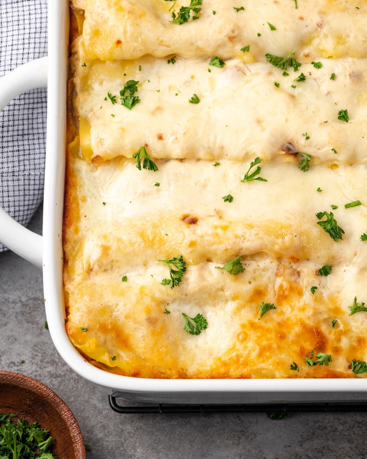 Lasaña cremosa de pollo rebosante de capas de pollo jugoso, fideos tiernos y salsa blanca casera sedosa con abundante queso derretido. Cerca de una esquina de lasaña de pollo en una cacerola.