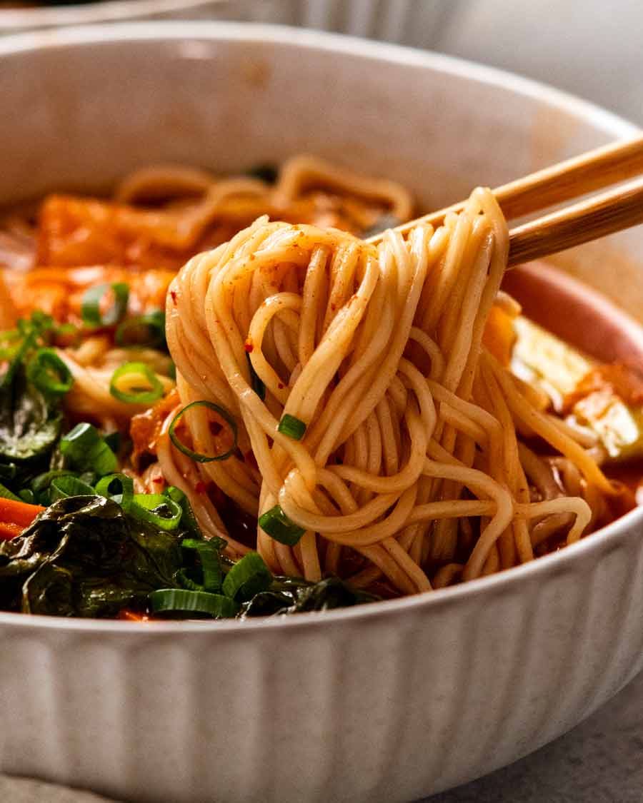 Palillos recogiendo fideos en sopa de fideos coreana picante