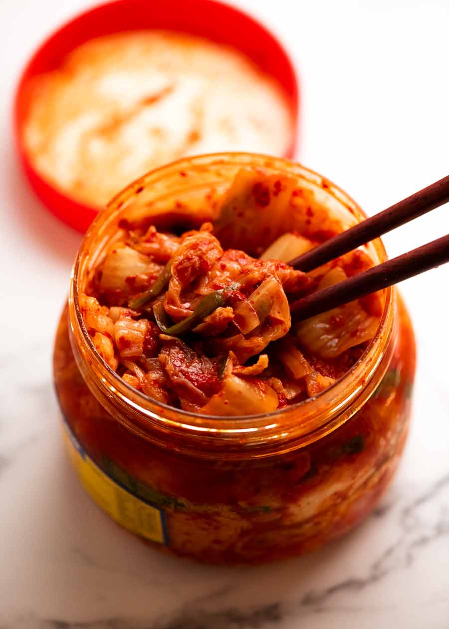 Cerca de palillos recogiendo kimchi para hacer arroz frito con kimchi