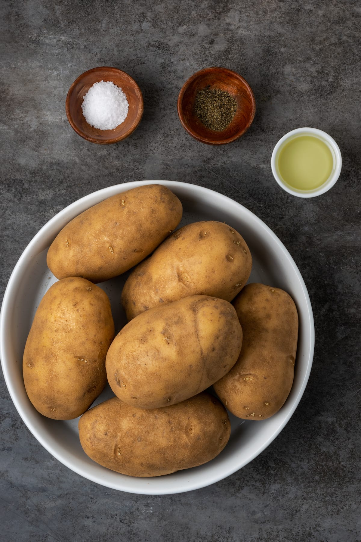 ¡Esta receta de papas al horno Crock Pot es un método más fácil para cocinar su guarnición de vegetales favorita sin encender el horno! Los ingredientes para las papas al horno con olla de barro.