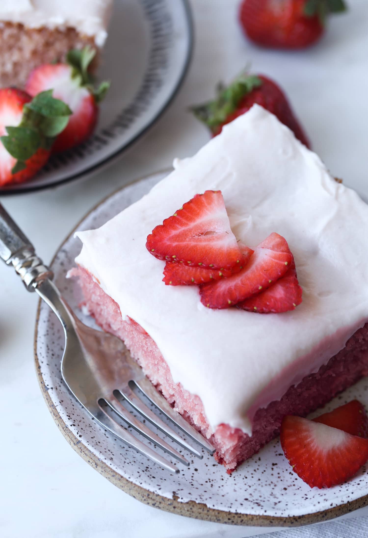 ¡Aproveche al máximo su recorrido de fresas de temporada con recetas de fresas de verano! Estos son los mejores postres y golosinas de fresa para probar. un trozo de tarta de fresa en un plato desde arriba con rodajas de fresa fresca