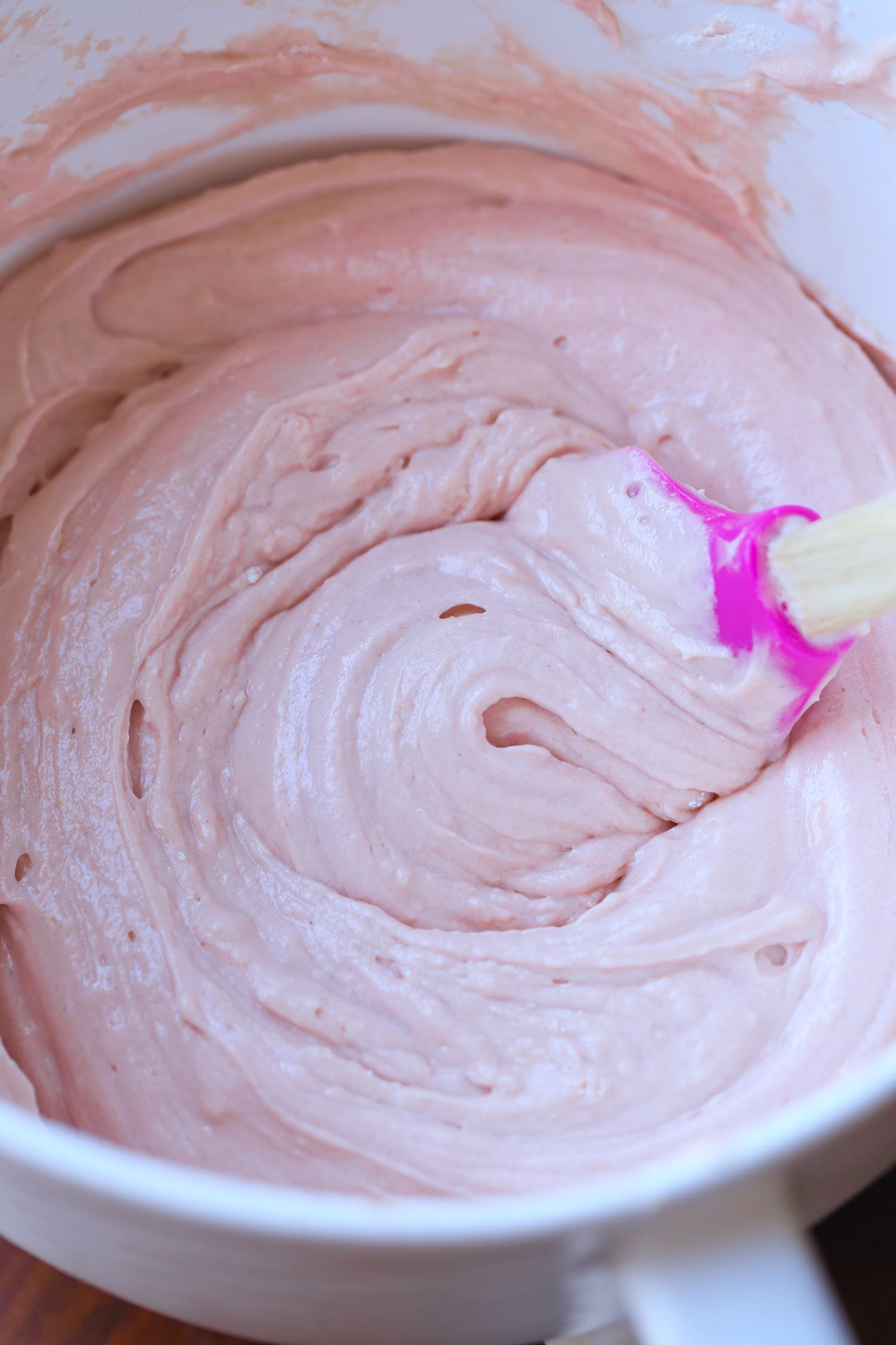 glaseado de queso crema de fresa en un tazón con una espátula