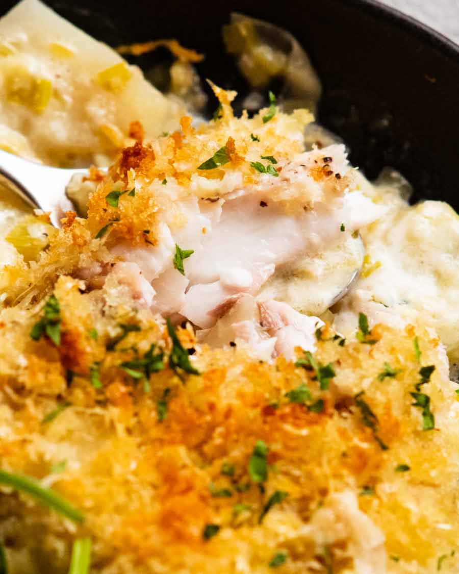 Primer plano que muestra suculento pescado cremoso sobre patatas gratinadas