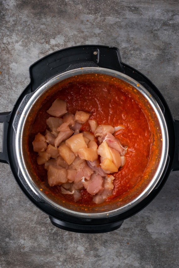 Trozos de pollo agregados a la salsa de tomate dentro de la olla instantánea.