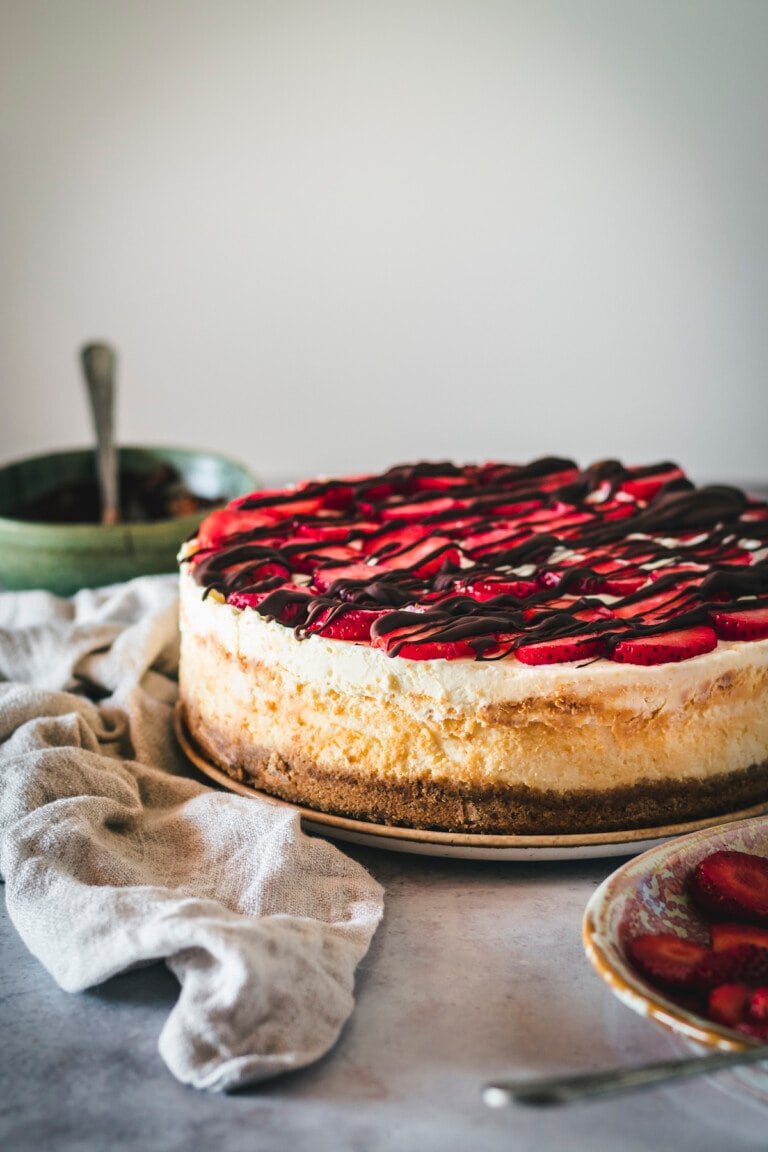 Cheesecake de fresa cubierto de chocolate en un plato.