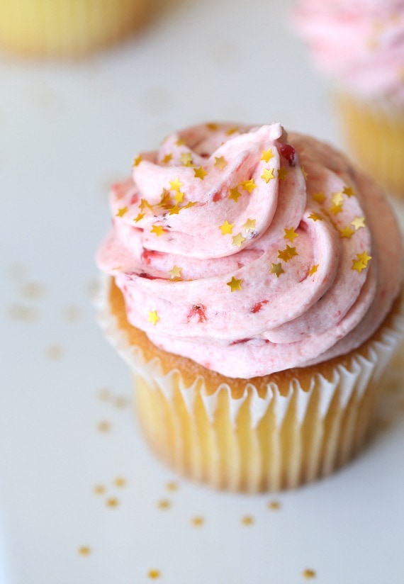 Un cupcake de vainilla cubierto con un remolino de glaseado de crema de mantequilla de fresa.