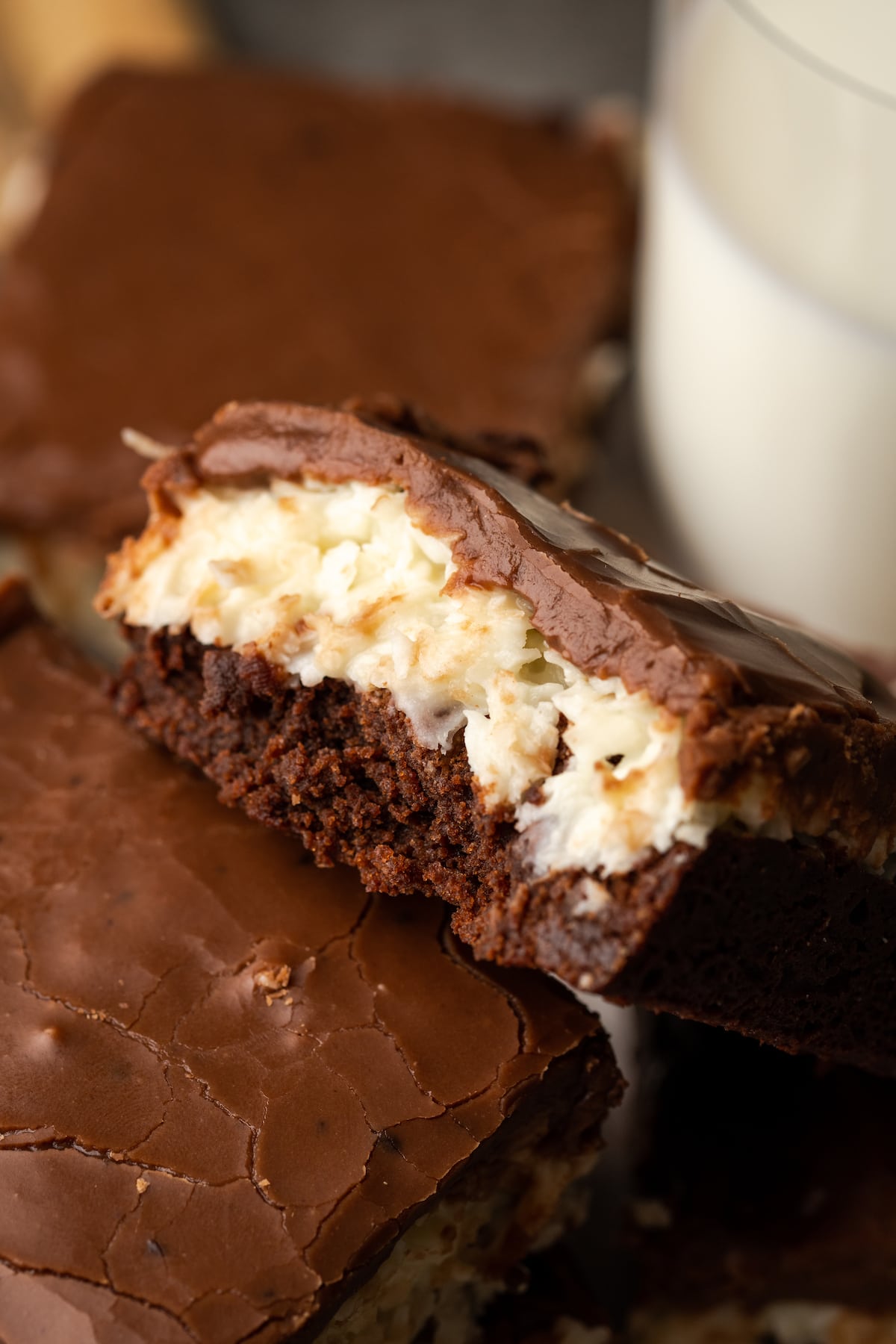Primer plano de un brownie de coco apoyado contra otro brownie, mostrando la capa de coco.