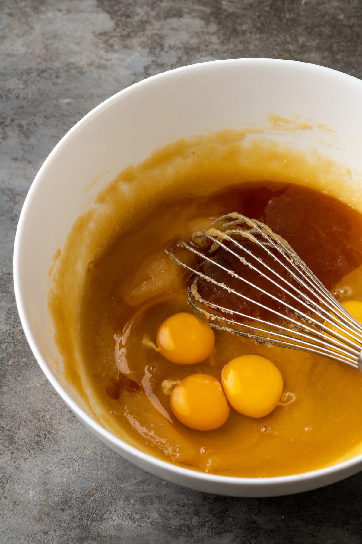 Los huevos y la vainilla se mezclan con la crema de azúcar y la mantequilla en un tazón.
