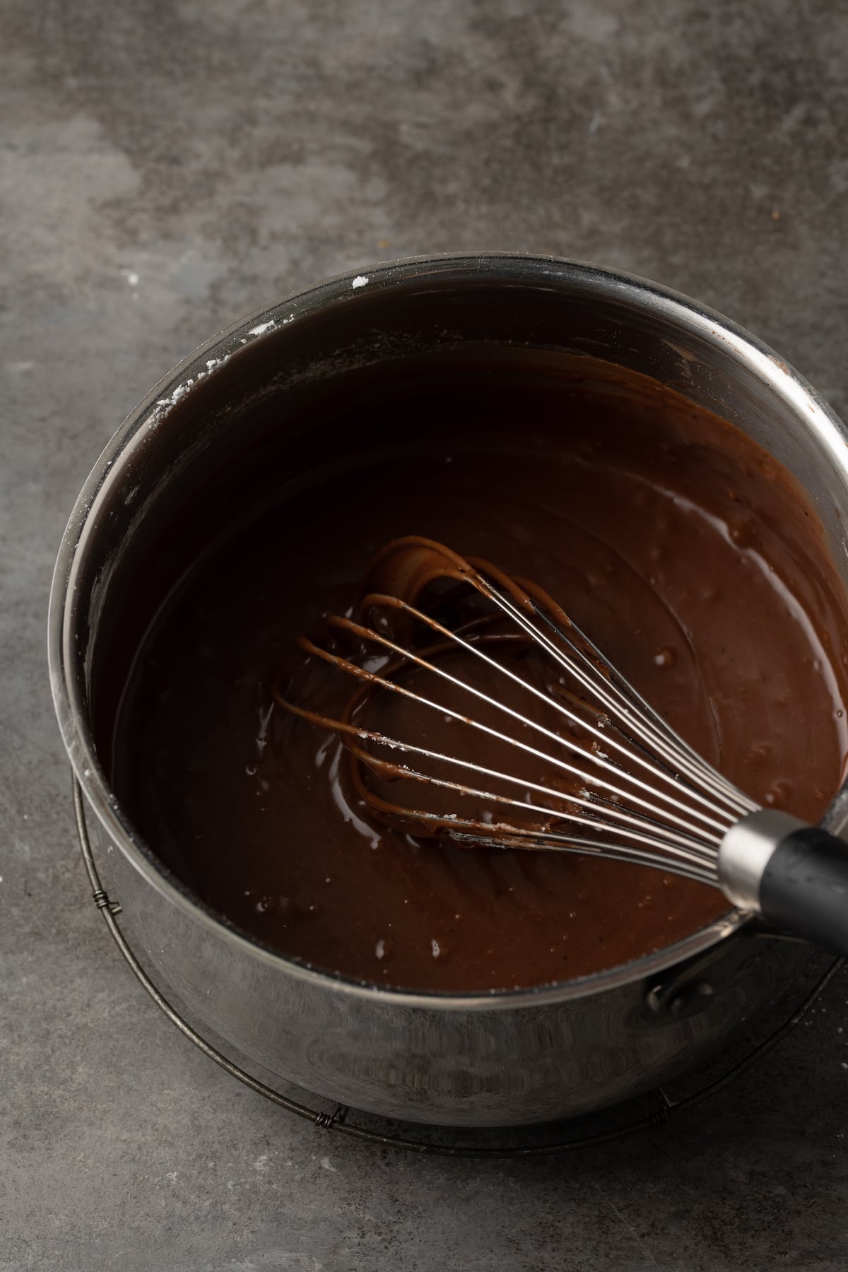 Glaseado de chocolate en una cacerola con un batidor.