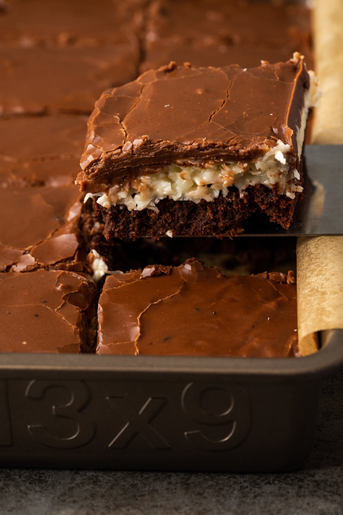 Un brownie de coco se levanta de una bandeja para hornear de brownies.