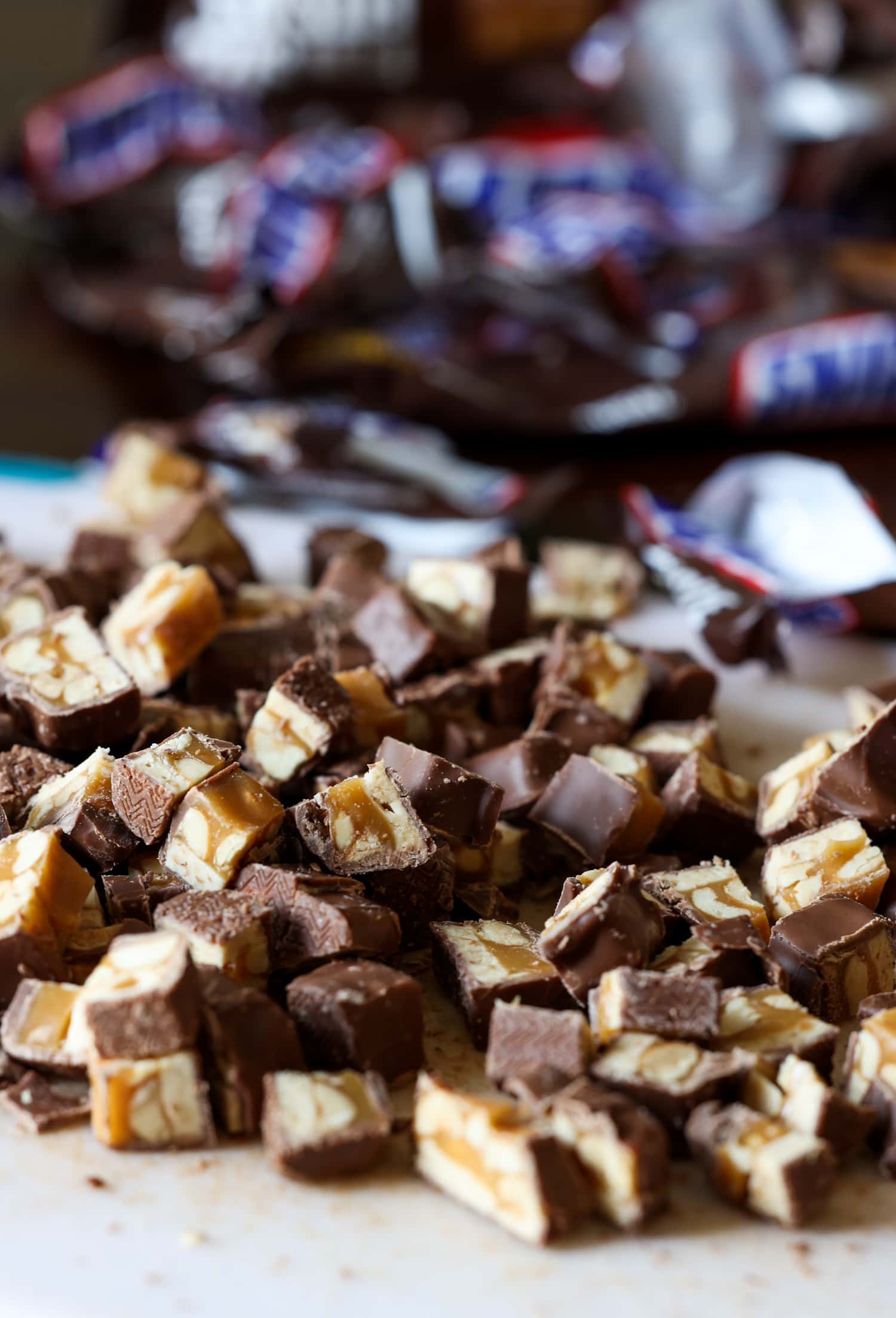snickers picados en una tabla para cortar con envolturas en el fondo