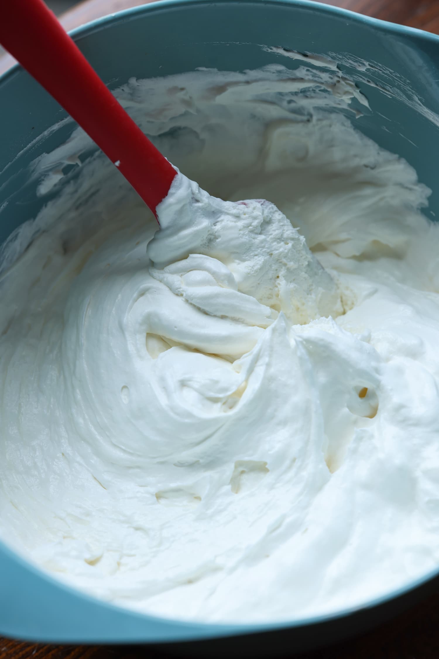 mezcla de mousse de queso crema en un tazón azul con una espátula de goma