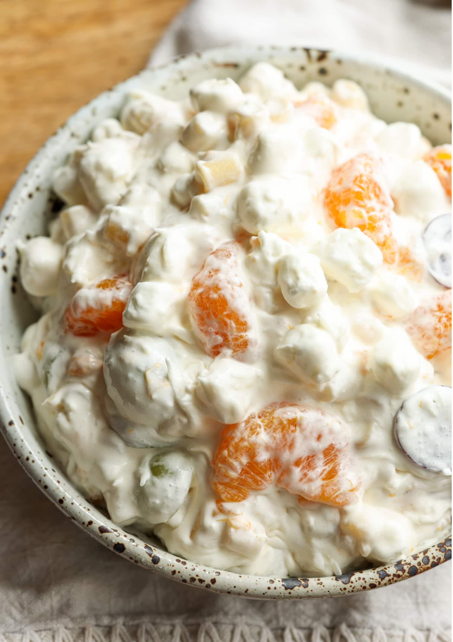 Frog Eye Salad es una ensalada dulce de verano con fruta, natillas, cobertura batida y pasta. ¡Es una delicia de textura y sabor, y es la receta de guarnición perfecta para su barbacoa de verano! Ensalada de ojos de rana en un bol con mandarinas