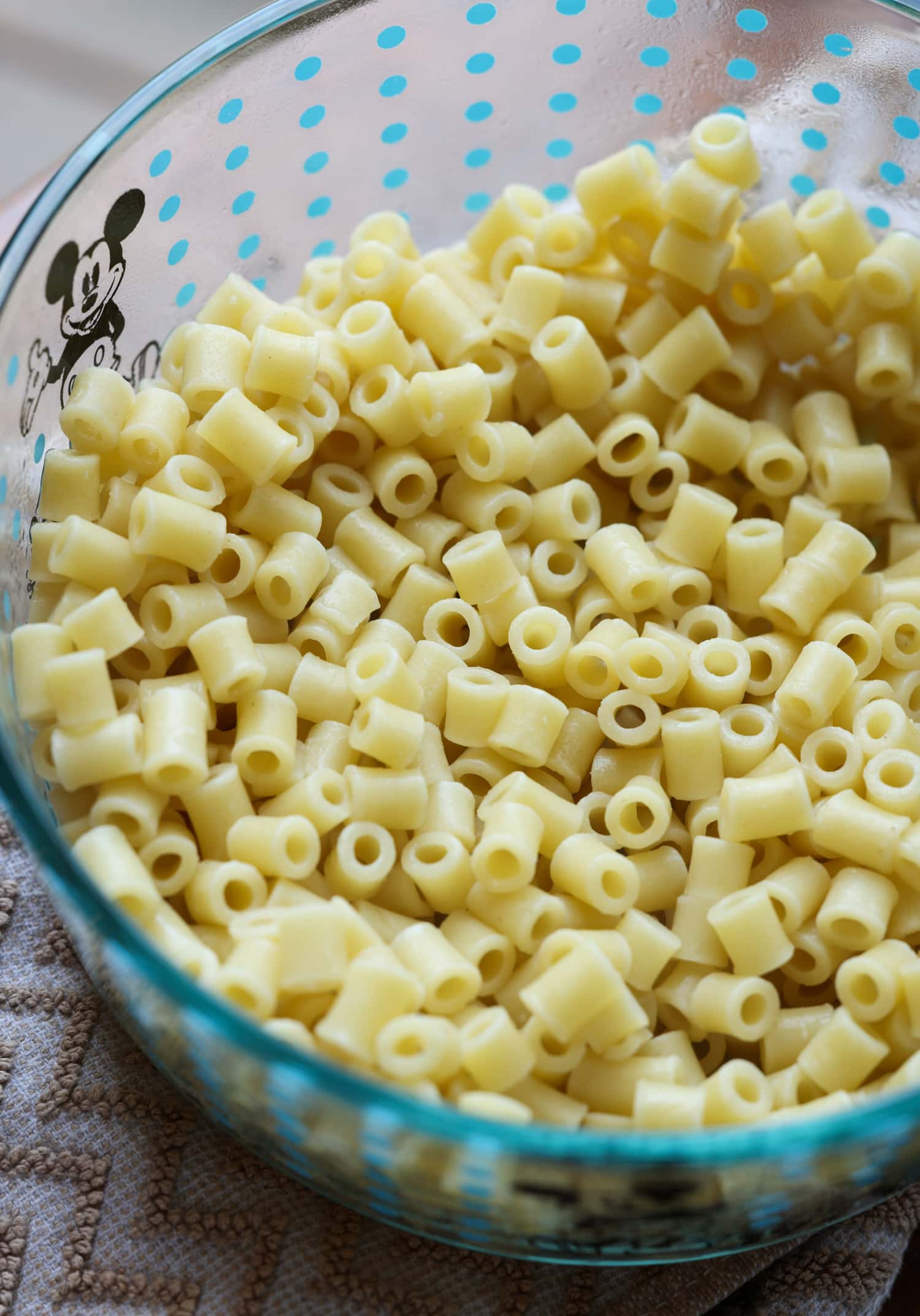Frog Eye Salad es una ensalada dulce de verano con fruta, natillas, cobertura batida y pasta. ¡Es una delicia de textura y sabor, y es la receta de guarnición perfecta para su barbacoa de verano! pasta ditalini cocida en un bol