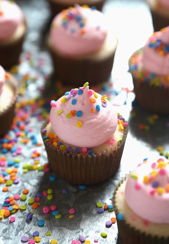 pastel funfetti con un glaseado rosa claro en la parte superior y chispas de quin por todas partes