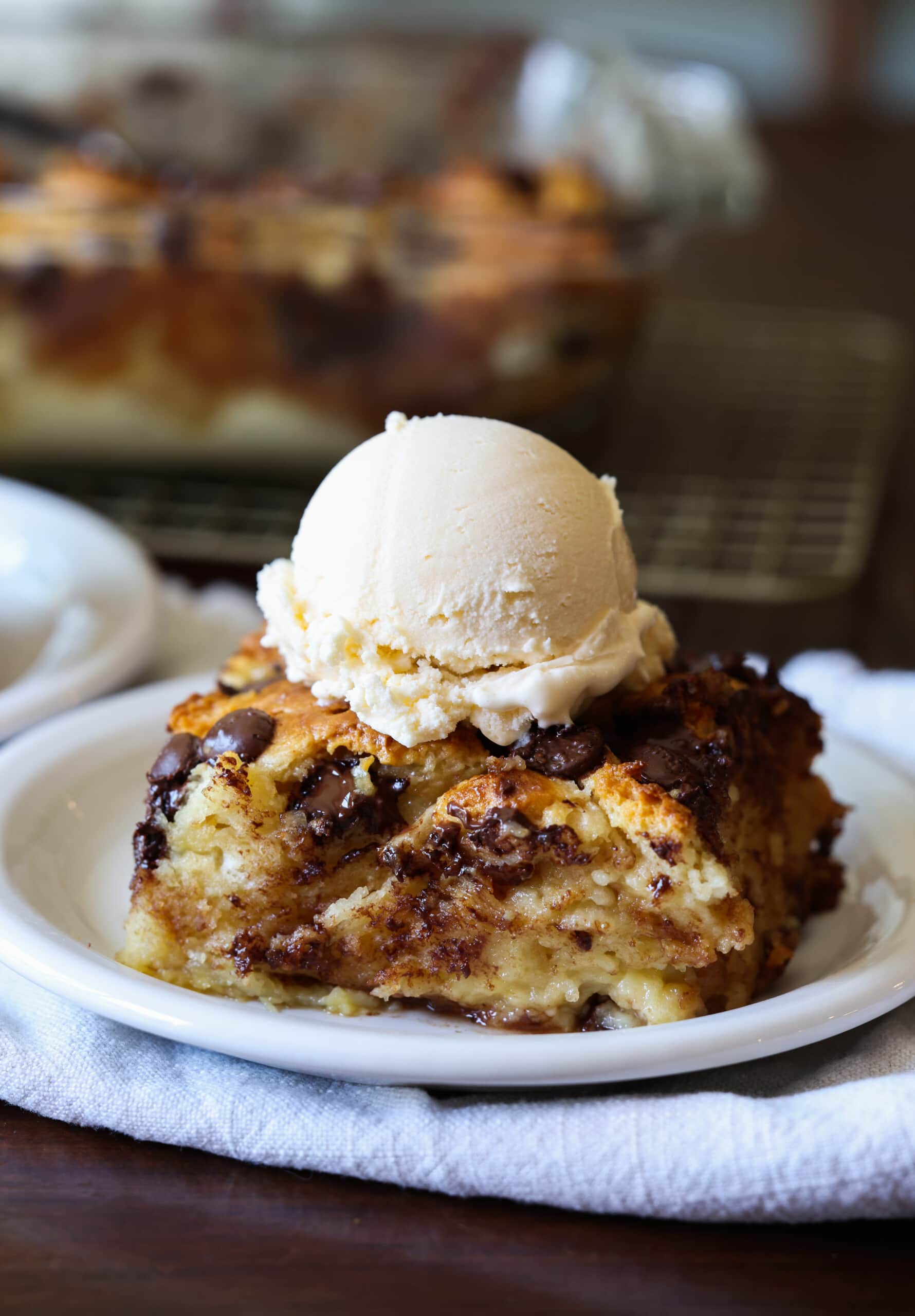 Un pudín de pan hecho con galletas del día anterior en un plato blanco con helado de vainilla.