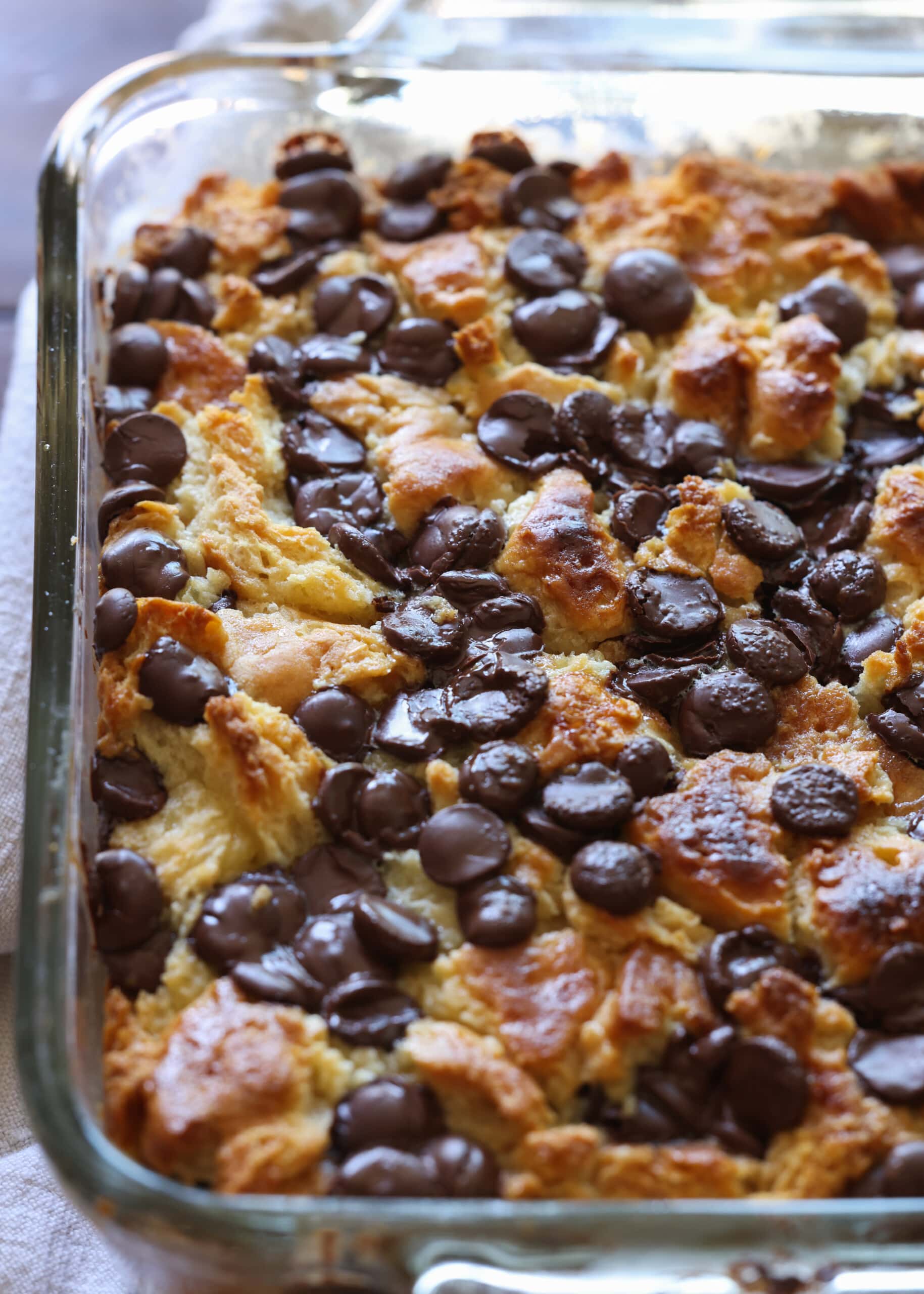 Budín de pan hecho con galletas y cubierto con chispas de chocolate horneado en un molde de 8x8.