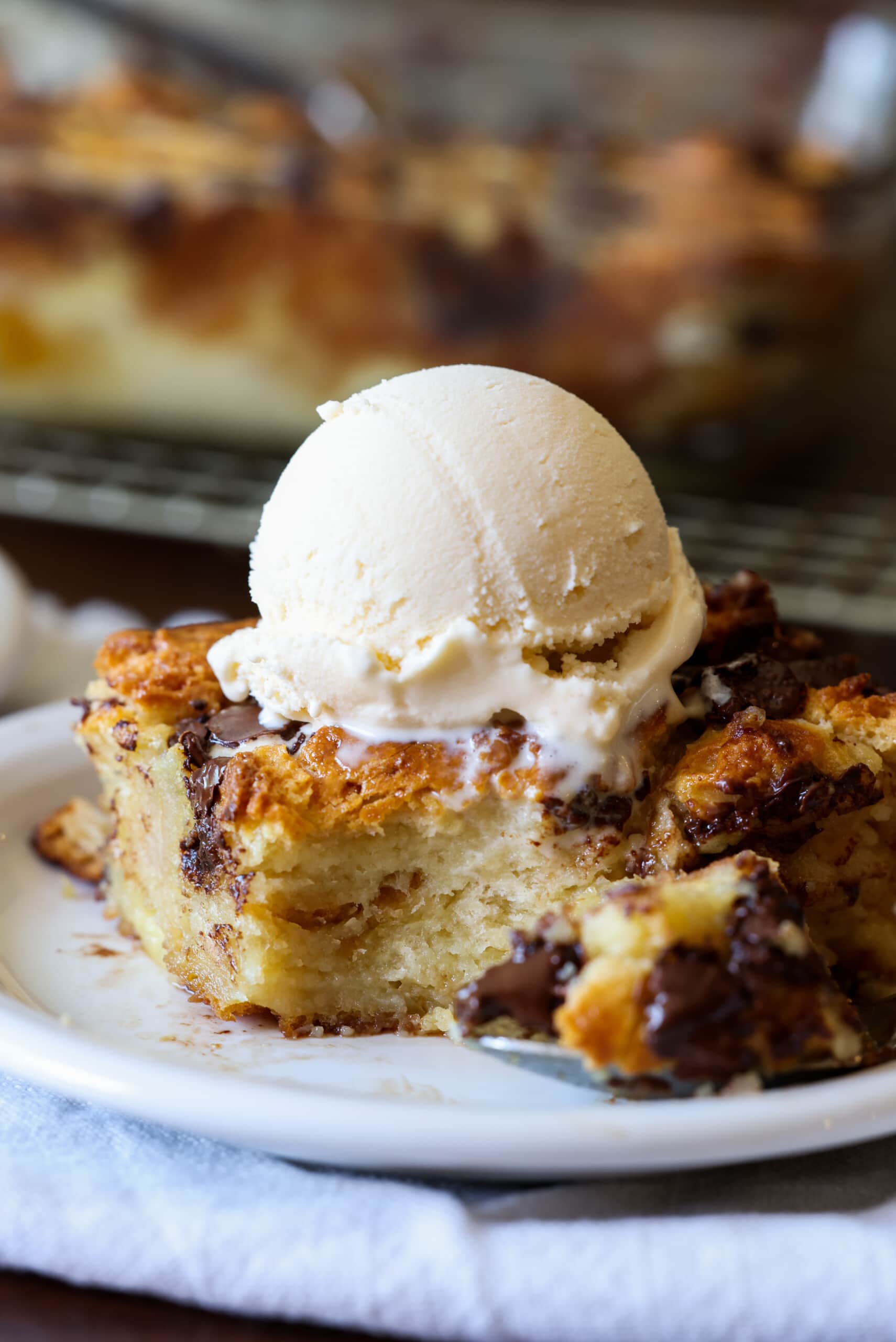un trozo de budín de pan hecho con galletas en un plato cubierto con helado con una cucharada sacada