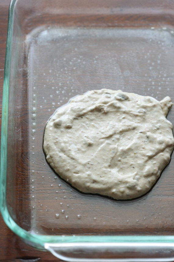 salsa de enchilada de crema agria en el fondo de un plato de vidrio pyrex de 9x13