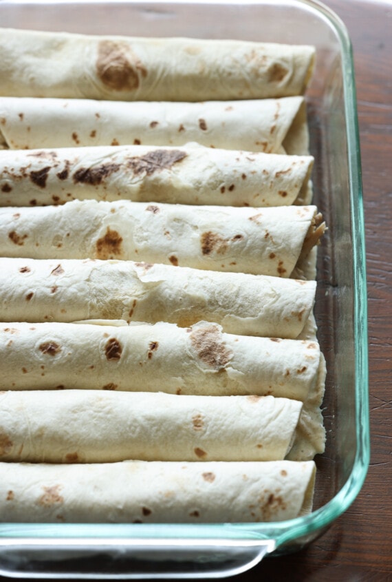 tortillas enrolladas en una fuente para hornear llena de pollo