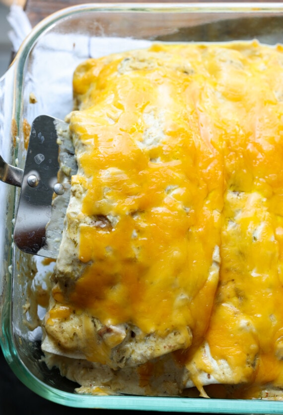 Sirviendo enchiladas de pollo con queso en una cacerola con una espátula