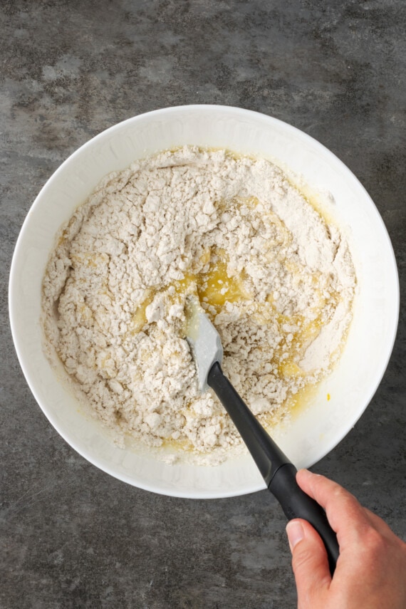 Los ingredientes para la masa de bizcocho de limón se mezclan en un tazón blanco con una espátula.