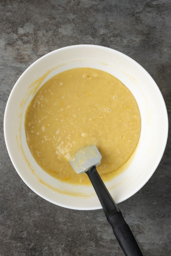 Masa de bizcocho de limón en un recipiente blanco con una espátula.