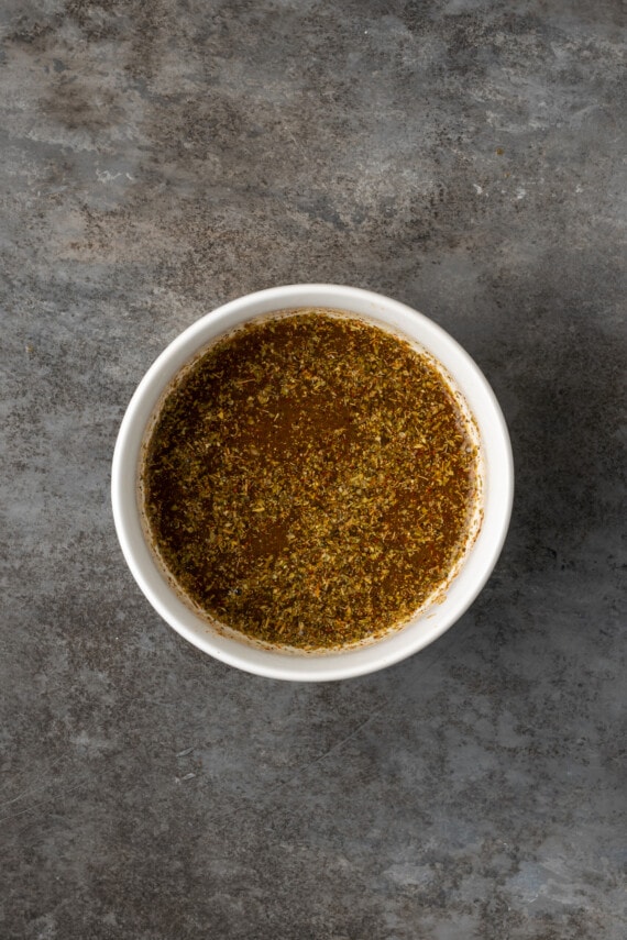 ¡Esta receta de Instant Pot Carnitas necesita solo 5 minutos de preparación! Haga carnitas increíblemente tiernas, jugosas y crujientes para tacos de cerdo y más. Condimento combinado con aceite de oliva en un molde blanco.