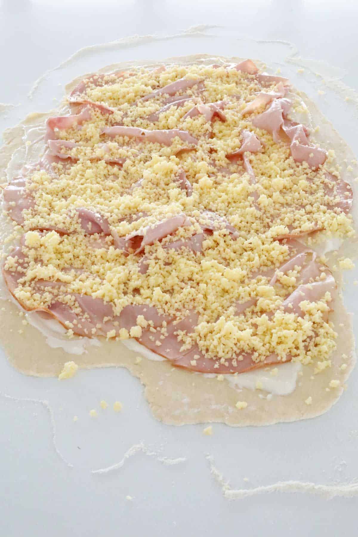 Masa con jamón y queso rallado encima.