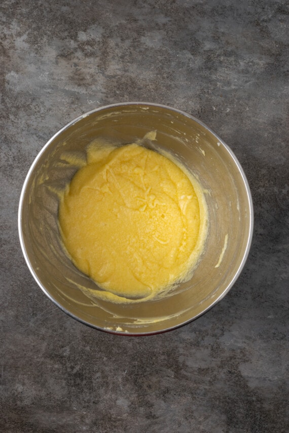 Esta receta de bizcocho Victoria es suave, esponjosa y está hecha con ingredientes simples. ¡Perfecto para combinar con mermelada y crema batida casera! Ingredientes de masa de bizcocho combinados en un tazón de metal.