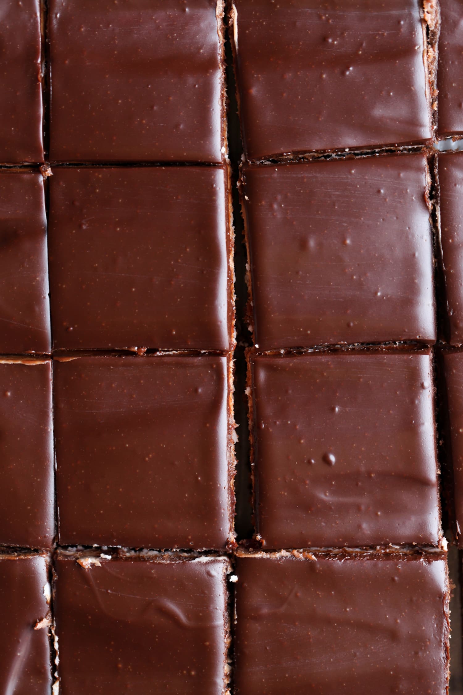 Brownies en rodajas cubiertos con ganache en rodajas en un molde para hornear de 9x13 que se muestra desde arriba
