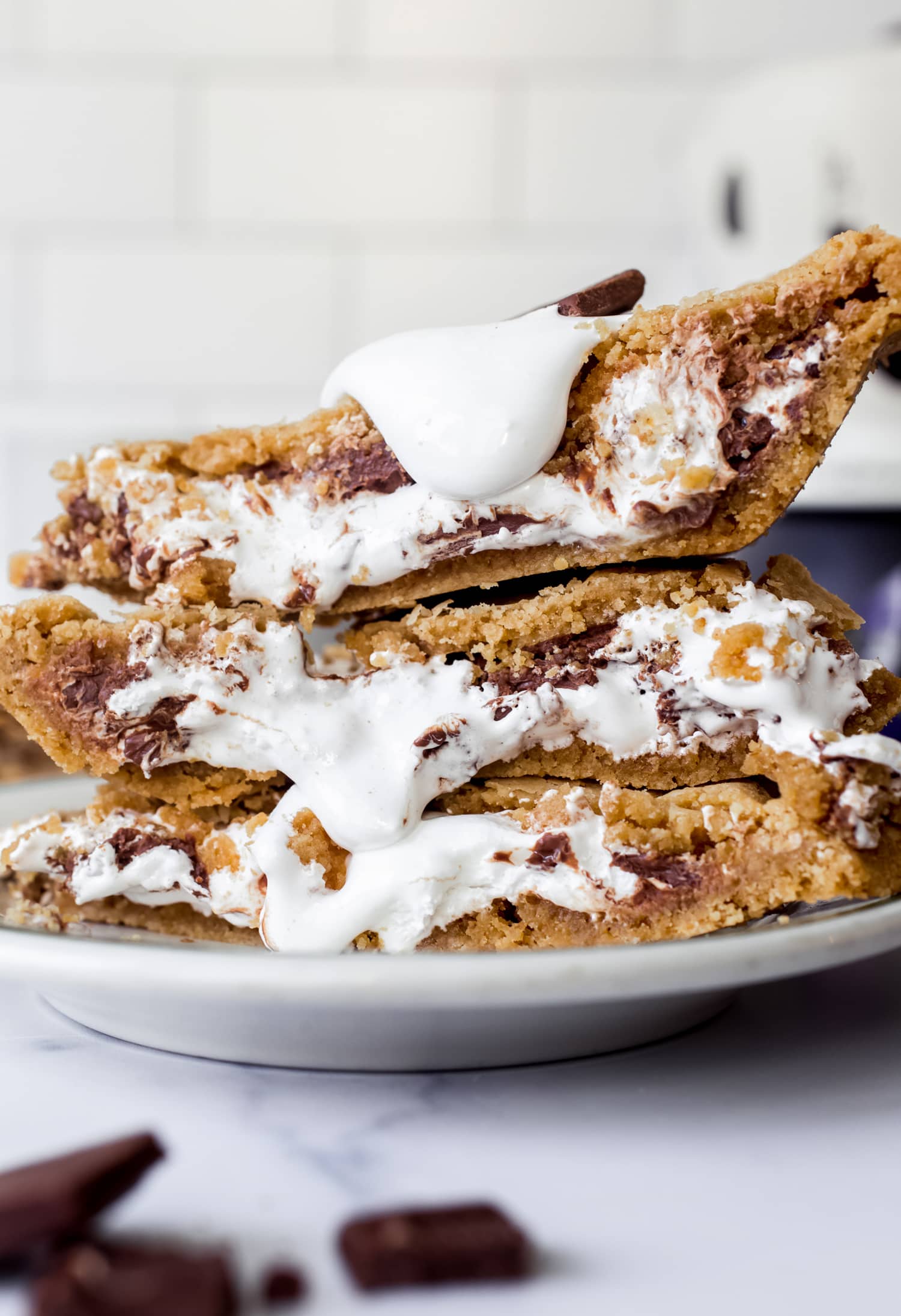 ¡Esta receta de Smores Pie es escandalosamente deliciosa! ¡La corteza de galleta Graham enrollada es única y fácil, y el pastel está lleno de malvavisco pegajoso y chocolate derretido! ¡Como una rebanada gigante de smores sin necesidad de fogata! Pedazos apilados de pastel de s'mores en un plato con crema de malvavisco rezumando